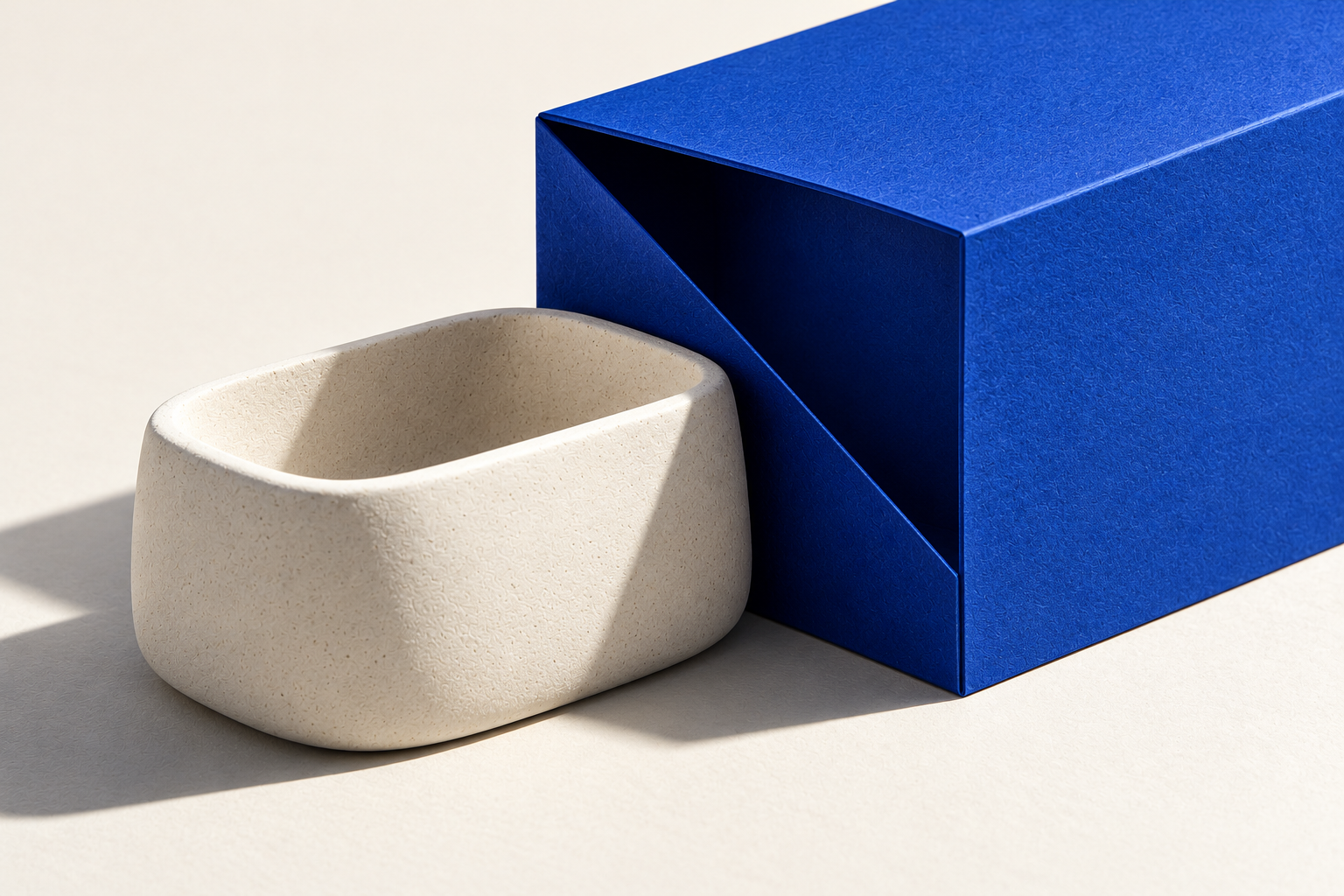 Concept study of a cobalt paper sleeve and a white sculptural vessel.
